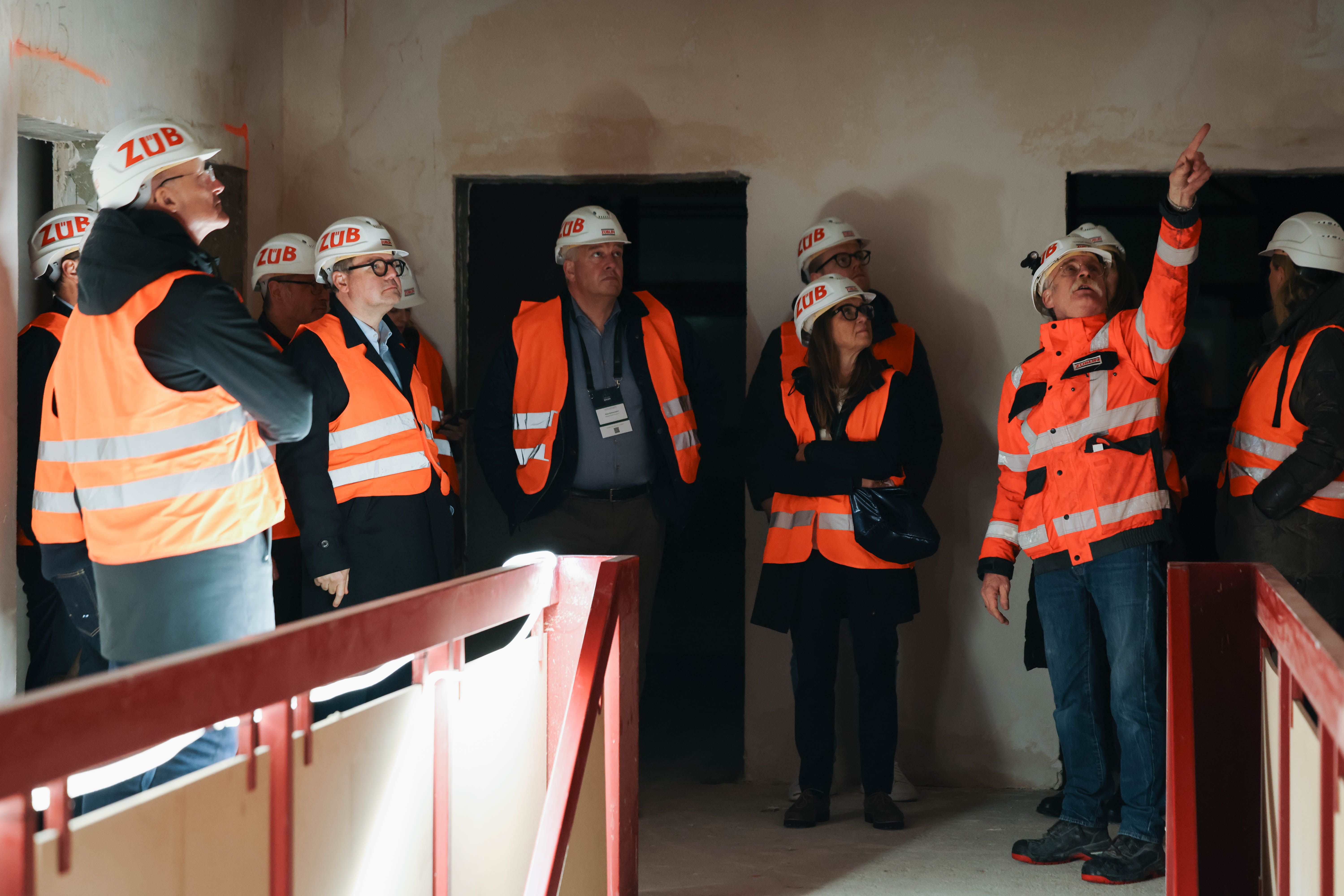 Gruppe von Personen in Schutzkleidung und Helmen auf einer Baustellenführung