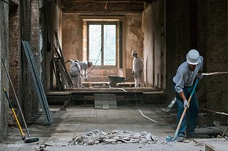 Bauarbeiter bei der Arbeit innerhalb einer Kernsanierung in einem alten Gebäude