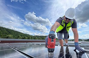 Mitarbeiter befestig Solarpanel auf dem Dach