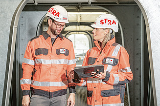 Zwei STRABAG Baustellenmitarbeiter Zu sehen sind zwei STRABAG Baustellenmitarbeiter die sich über Sanierung und Umbau einer Bestandsimmobilie unterhalten