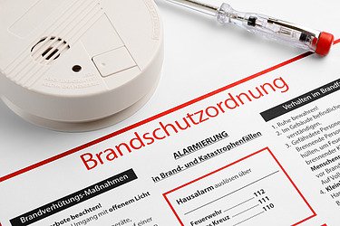 Brandschutzordnung und Feuermelder mit Schraubenzieher auf einem Tisch in Nahaufnahme