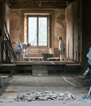 Bauarbeiter bei der Arbeit innerhalb einer Kernsanierung in einem alten Gebäude