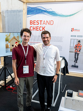 Zwei männliche Personen vor dem Messestand Bestand Check